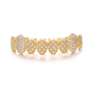 Macro shot of gold hip hop grillz with shimmering inlaid diamonds on white background
