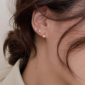 Gros plan sur des puces d'oreilles en argent s925 avec zircon et créoles dorées sur modèle