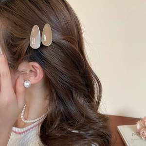 Détail de barrettes en acrylique marron clair et boucles d'oreilles perles sur mannequin