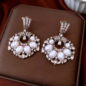 Vintage gold dangle earrings with pearls and rhinestones on luxury jewelry box