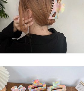 Colorful acetate claw clip with tie-dye pattern shown on hair and tabletop setup