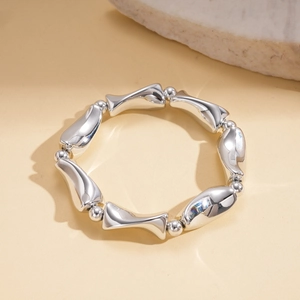 Detail of silver-tone organic geometric bead bracelet on a beige textured background