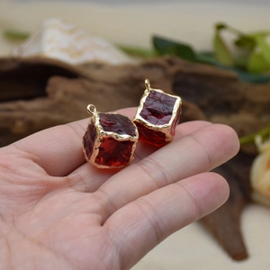Vintage style red resin cube pendants with gold trim displayed in a person's hand