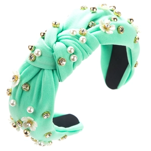 Détail d'un serre-tête noué vert menthe orné de perles blanches et de fleurs en cristal