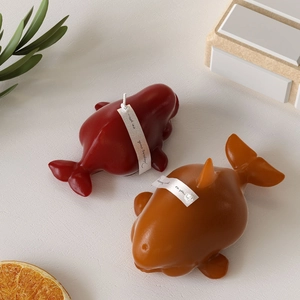 Detailed close-up of whale-shaped aromatherapy candles in red and amber on a display stand