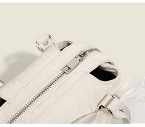 Détail de fermeture éclair argentée et nœud en organza sur un sac Boston blanc