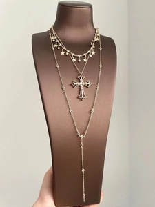 Detail view of gold tiered necklace set with cross pendant and tassel layering