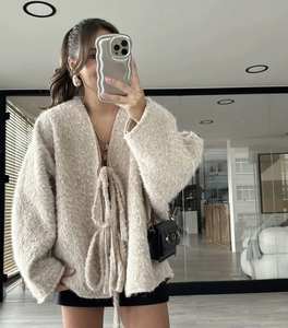 Detail of soft cream knitted cardigan with tie-front closure and fluffy texture