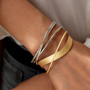Detail of layered geometric crossover bangles in gold and silver finish on model
