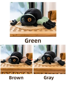 Plush spider toys in green, brown, and grey with embroidered eyes on a woven mat