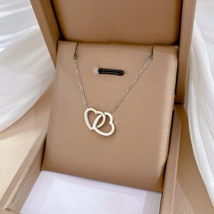 Minimalist silver dual heart titanium steel necklace displayed in a beige jewelry box