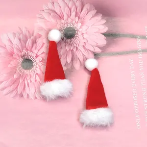 Vue détaillée de mini bonnets de Noël rouges en tricot avec pompons sur fond rose doux