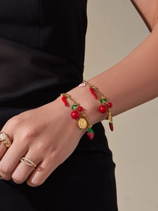 Détail d'un bracelet plaqué or 18 carats avec breloques cerise et fleur sur le poignet