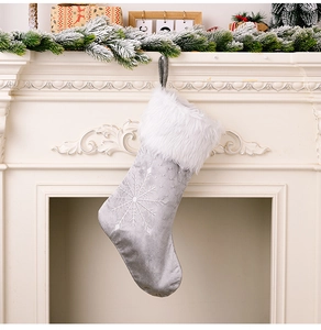 Détail d'une chaussette de Noël gris argenté avec flocons brodés sur une cheminée