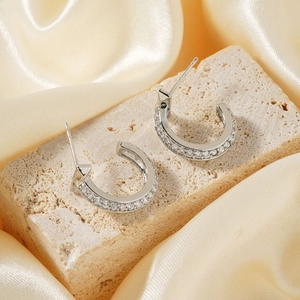 Elegant silver C-shaped stud earrings with pavé cubic zirconia on stone and satin background