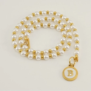 Macro view of 18K gold stainless steel necklace featuring a pearl shell letter B pendant