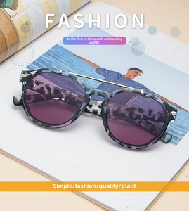 Close-up of double bridge sunglasses with tortoise frame and purple lenses on a magazine