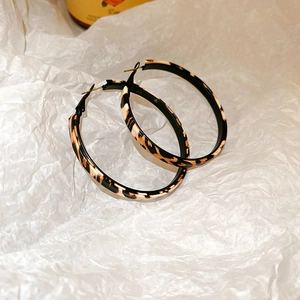 Close-up of leopard print large hoop earrings with animal pattern and silver needle closure