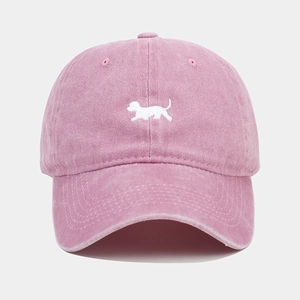 Détail d'une casquette de baseball rose délavée avec broderie chiot blanc et tissu texturé