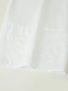 Detail view of exquisite white cotton linen embroidery and delicate tassels on the sleeve