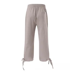 Detail of light brown linen pants featuring elastic waist and bow drawstring cuffs