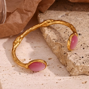 Close-up of golden irregular lava texture bracelet with pink oval stone settings