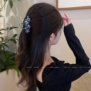 Détail d'une pince à cheveux à fleurs bleues avec strass portée sur une coiffure élégante