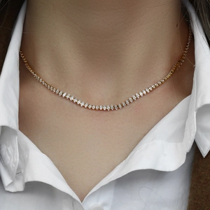Détail d'un collier tennis doré orné de zircons marquise porté par un mannequin