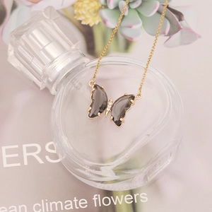 Close-up of a gold butterfly necklace with smoky translucent wings and micro-inlaid stones