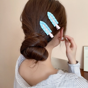 Detail of two macaron blue wave hair clips on a messy bun hairstyle side view