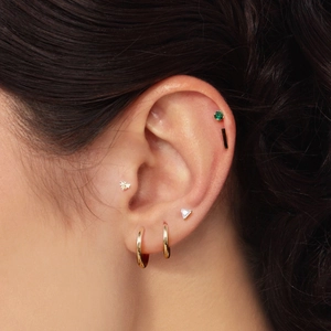 Macro view of gold geometric stud earrings with green gems and tiny bee design