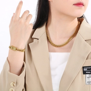 Golden curb chain necklace and bracelet set shown on model wearing a beige blazer