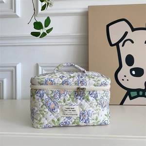 Détail d'une trousse à maquillage matelassée fleurie avec poignée et double zip