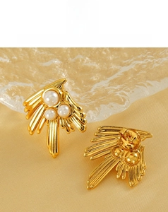 Detail of 18K gold swallow pearl earrings on ripple glass and champagne silk texture