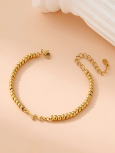 Detail of gold stainless steel beaded bracelet with wave charm and adjustable extension chain