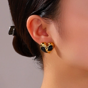 Fashionable heart-shaped gold and black drip oil earrings worn by a model