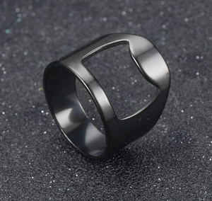 Close-up of black plated stainless steel bottle opener ring on dark textured surface