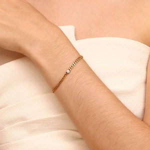 Close-up of a slim 18K gold-plated chain bracelet with a round zircon on a woman wrist