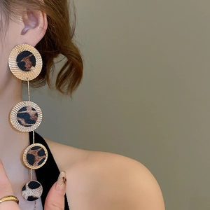 Close-up of leopard print drop earrings with gold metal rings and velvet texture on model