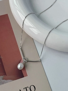 Detailed shot of a silver S925 knot necklace with a natural white freshwater pearl pendant