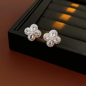 Gros plan de boucles d'oreilles trèfle en argent et zircons sur plateau noir