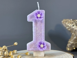 Close-up of number 1 purple glitter birthday candle with delicate 3D floral decorations