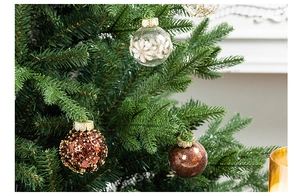Close-up of elegant Christmas ball ornaments with painted patterns on a green tree branch