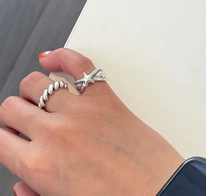 Close-up of minimalist 925 sterling silver rings with star and rope texture designs