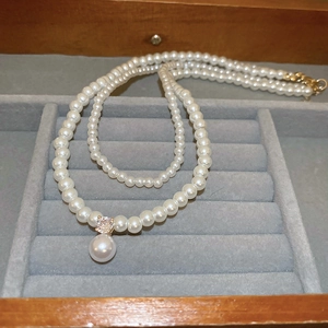 Detailed view of a double-layer pearl necklace with a teardrop pendant and zircon