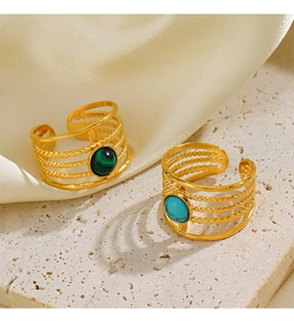 Detail of gold-plated rings with turquoise and malachite stones on textured stone