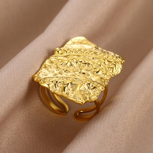 Macro detail of gold chunky ring with hammered texture on elegant silk background