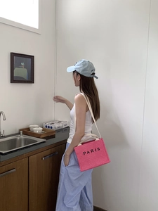 Pink woven straw tote bag with Paris text shown in a stylish minimalist lifestyle scene
