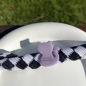 Détail d'une pince à cheveux chat violette avec lettrage doré sur chouchou à carreaux
