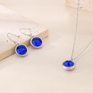 Detail of silver stainless steel jewelry set with blue round zircon stones on stones